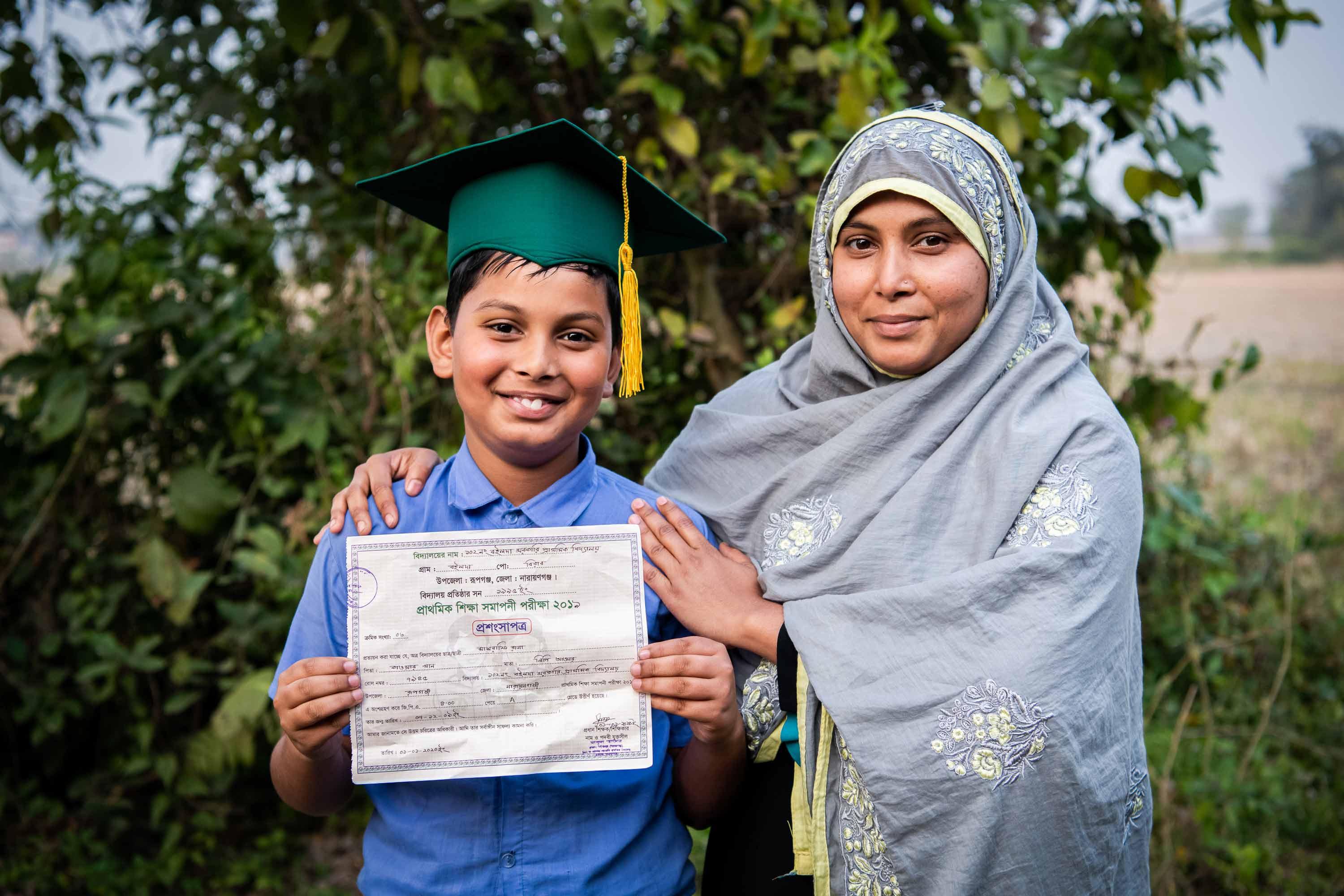 A student holding his graduation certificate with his mother